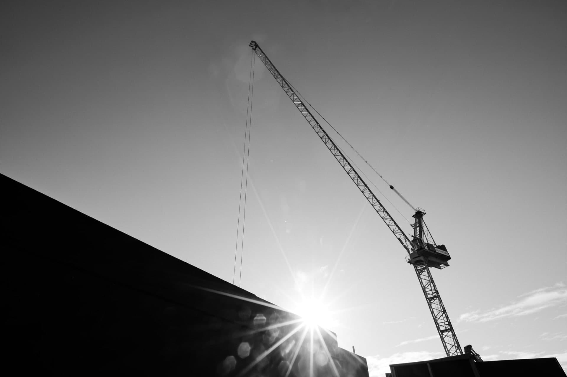 Tower crane silhouetted against the sun on a live construction site